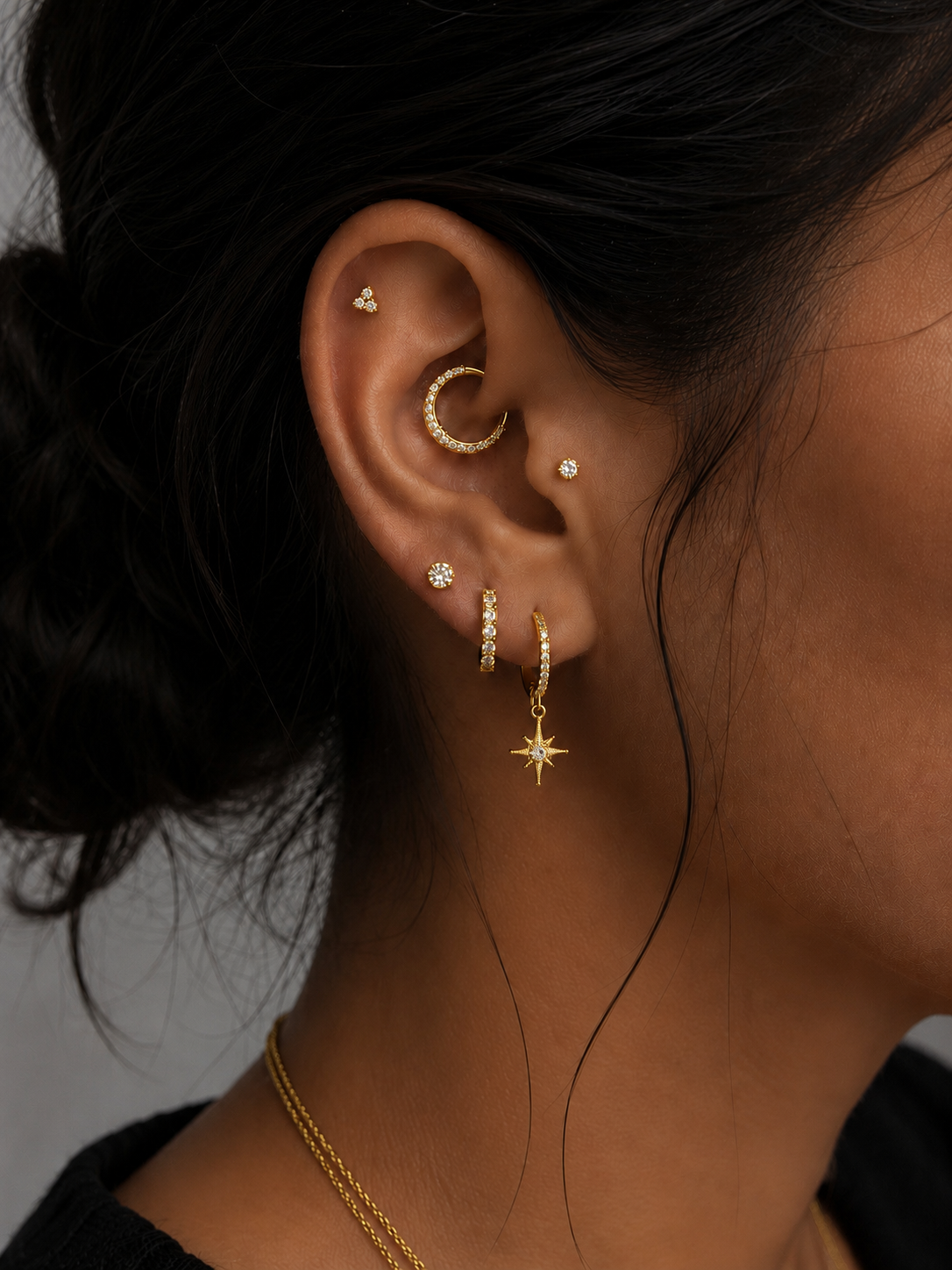 Oreille ornée de piercings dorés et bijoux délicats