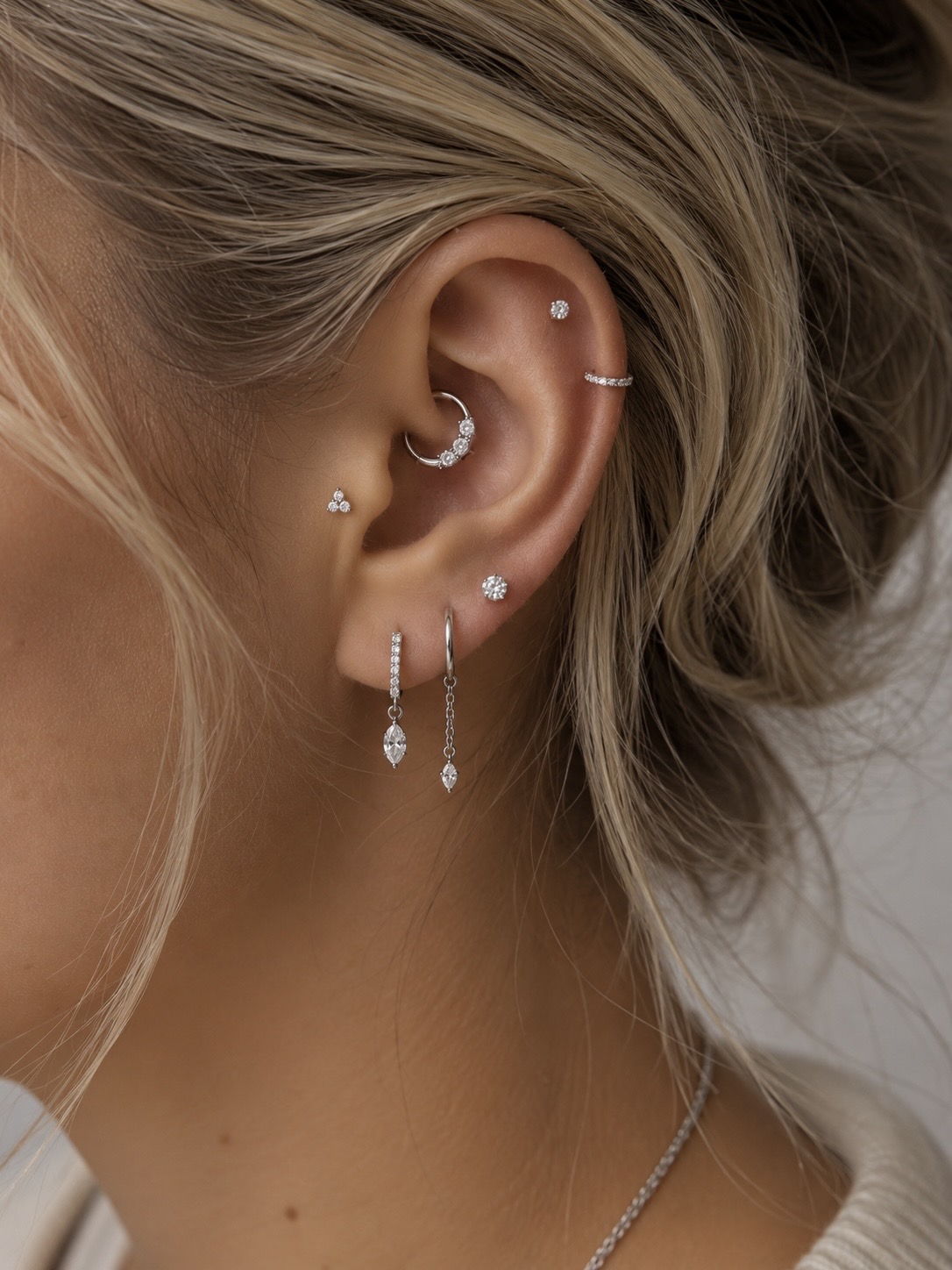 Oreille ornée de plusieurs piercings et bijoux délicats
